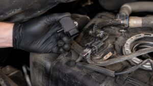 Technician inspecting a Ford EVAP pressure sensor during fuel vapor system diagnostics to diagnose check engine light and P0452 P0453 faults.