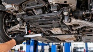 Mechanic inspecting vehicle subframe mounting points with a precision measuring tool to diagnose subframe alignment problems and suspension geometry issues.